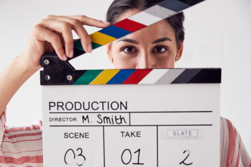 Portrait Of Female Videographer Holding Clapper Board On Video Film Production In White Studio